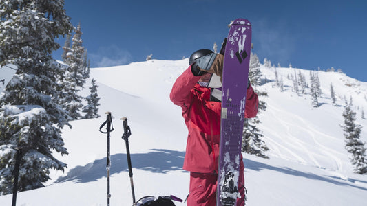 Skier pulling skins off Black Diamond skis at the top of the mountain.
