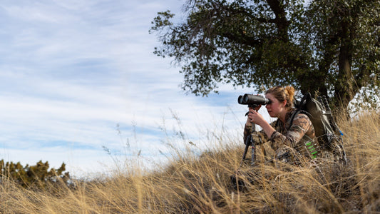 Person glassing with Maven B.5 binoculars in grassy field, under a tree.