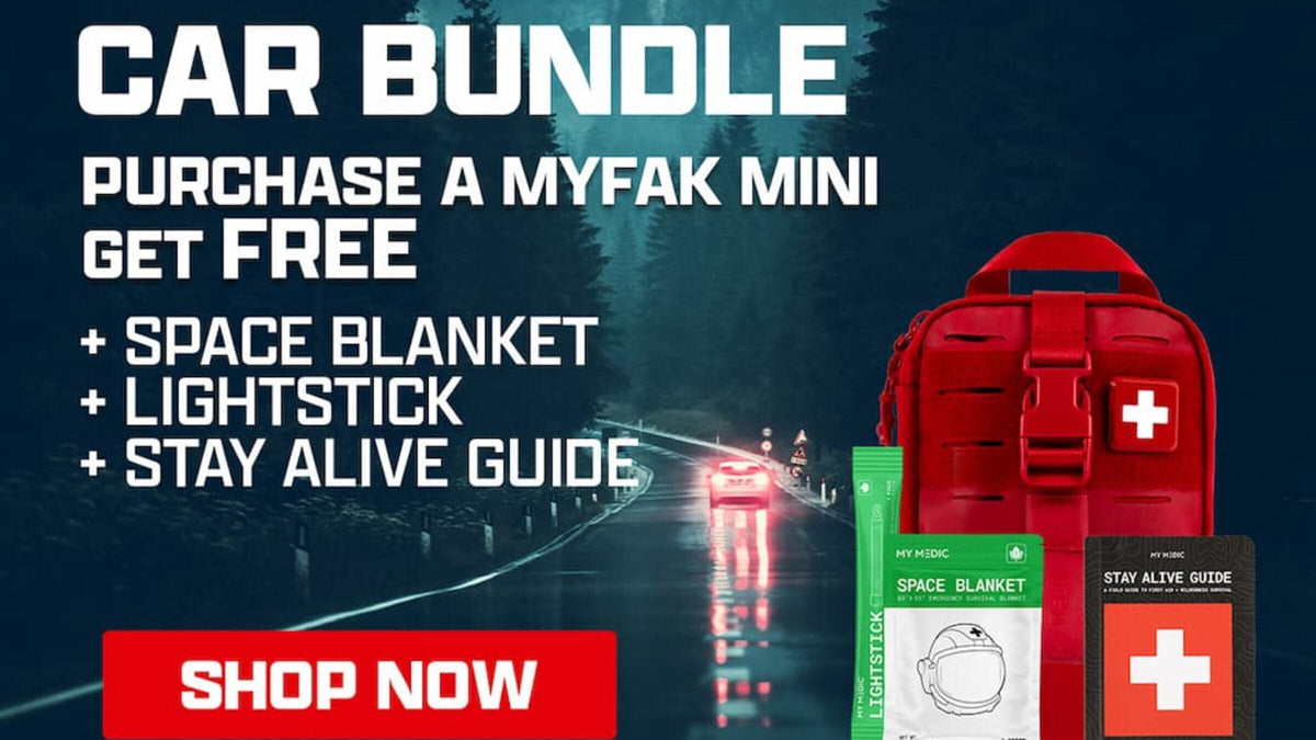 MyFAK Mini Car Bundle with a free Space Blanket, Lightstick, and Stay Alive Guide, shown against a rainy forest road at night